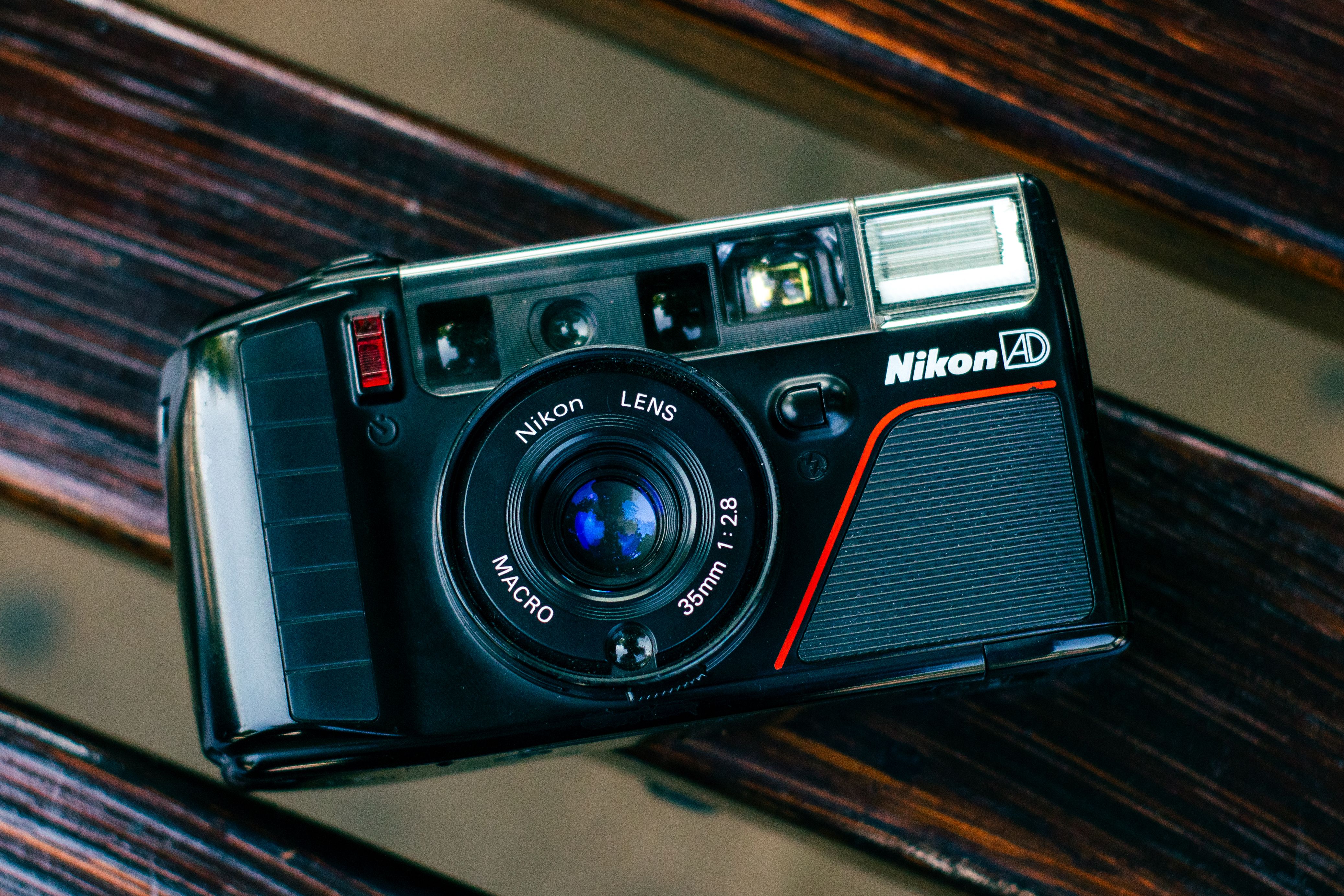 Close-up of vintage Nikon AD camera placed on a wooden bench, showcasing classic design and lens details.