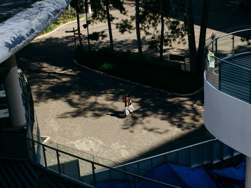 Free Top view of a person walking in a shadowed outdoor urban area surrounded by trees and buildings. Stock Photo