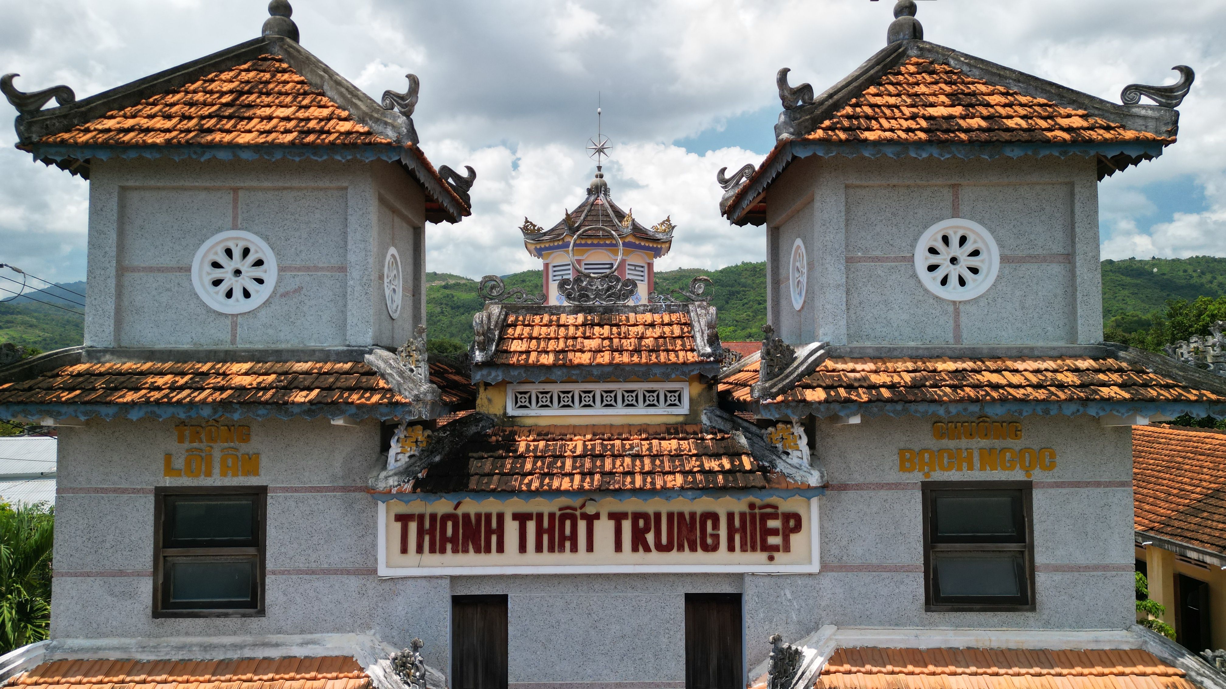 A beautiful Vietnamese temple featuring traditional architecture with intricate red-tiled roofs and decorative details under a blue sky.