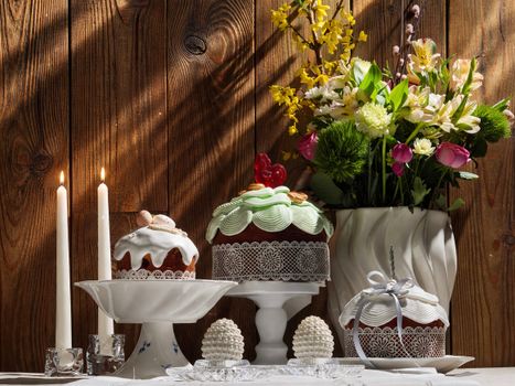 Elegant cakes and floral arrangement on wooden background create a festive ambiance.