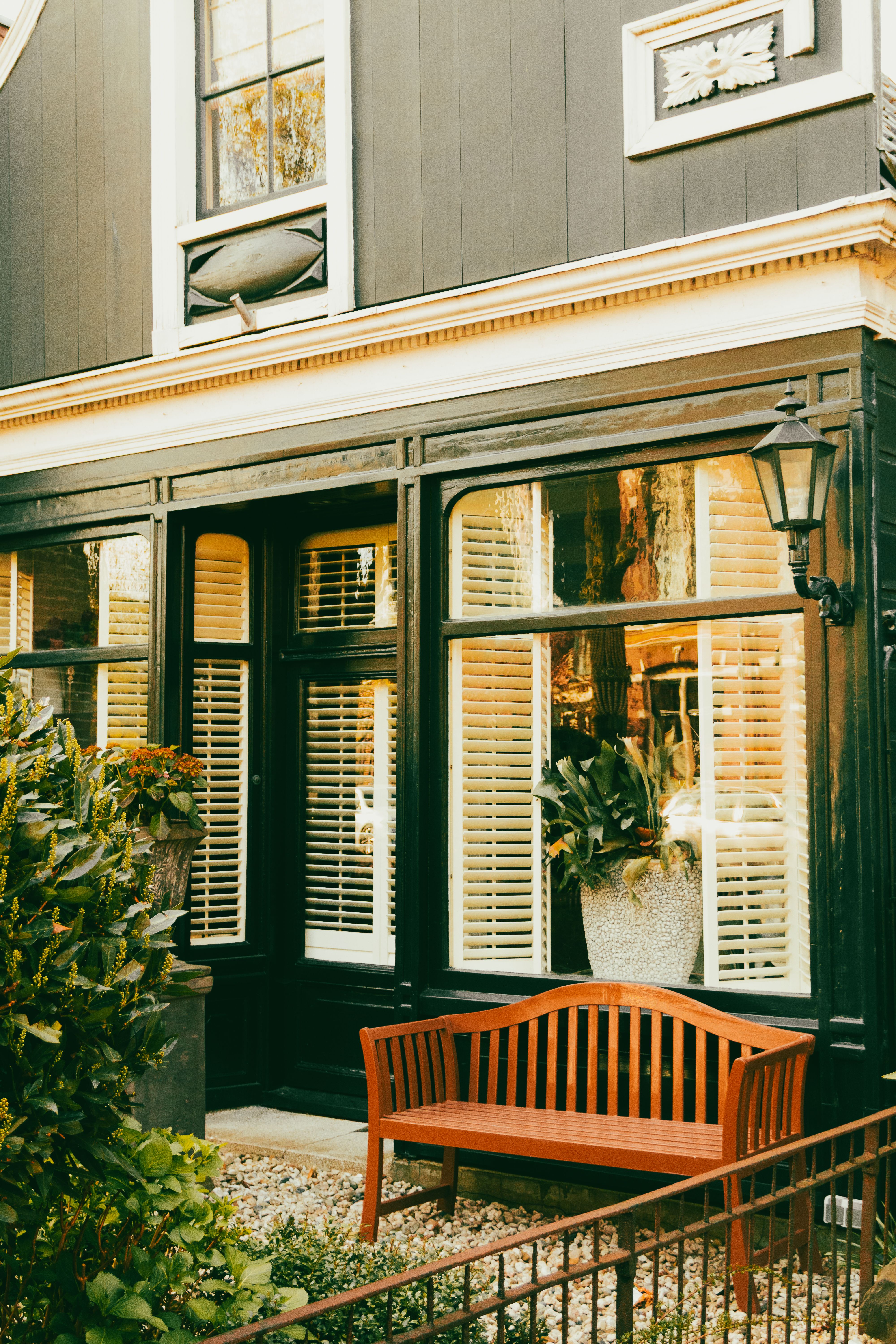 Elegant townhouse facade with wooden bench, large windows, and classic lantern for a cozy outdoor ambiance.