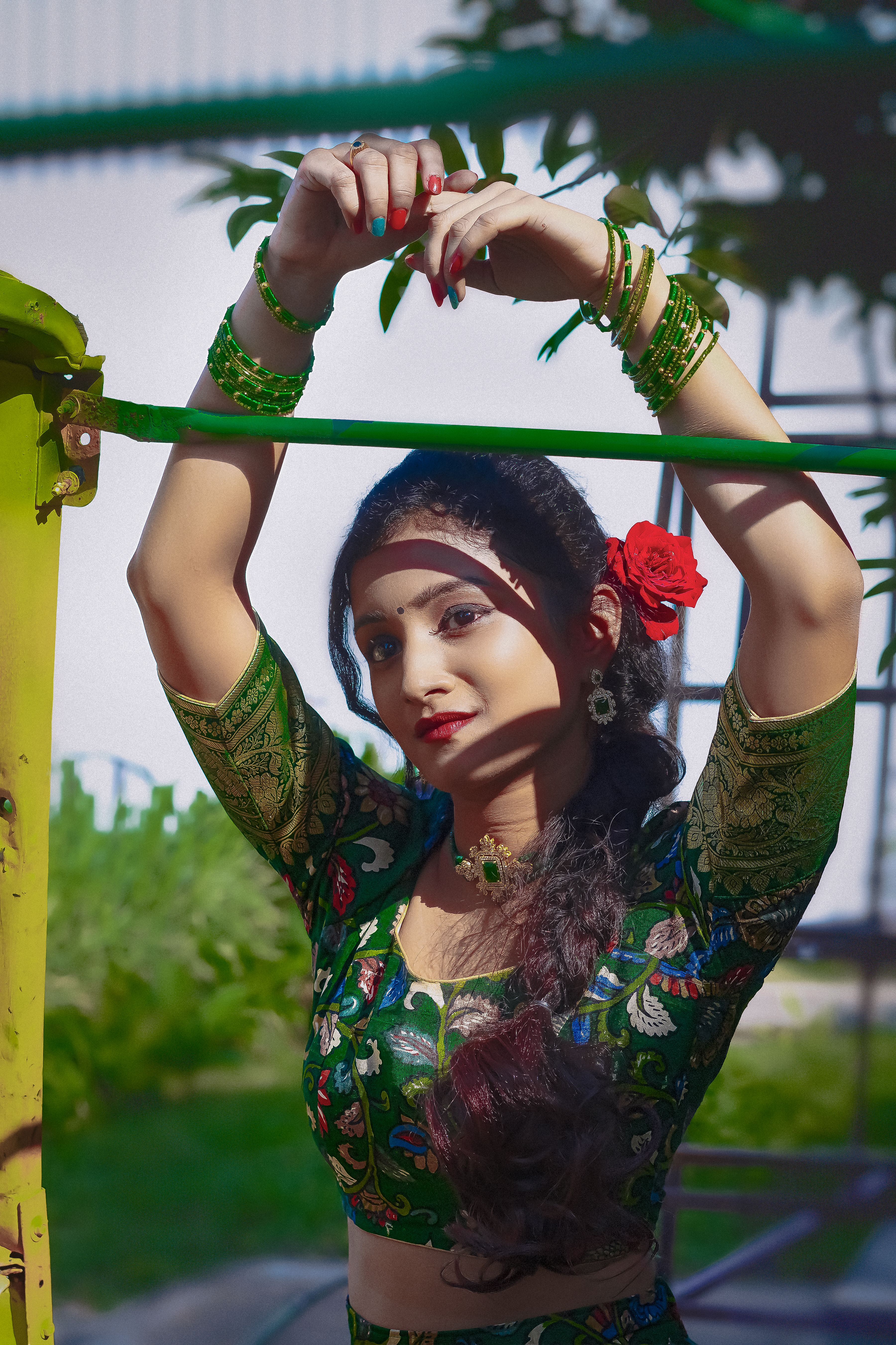 Portrait of a woman in vibrant Indian attire with floral accessories, photographed outdoors in Hyderabad.