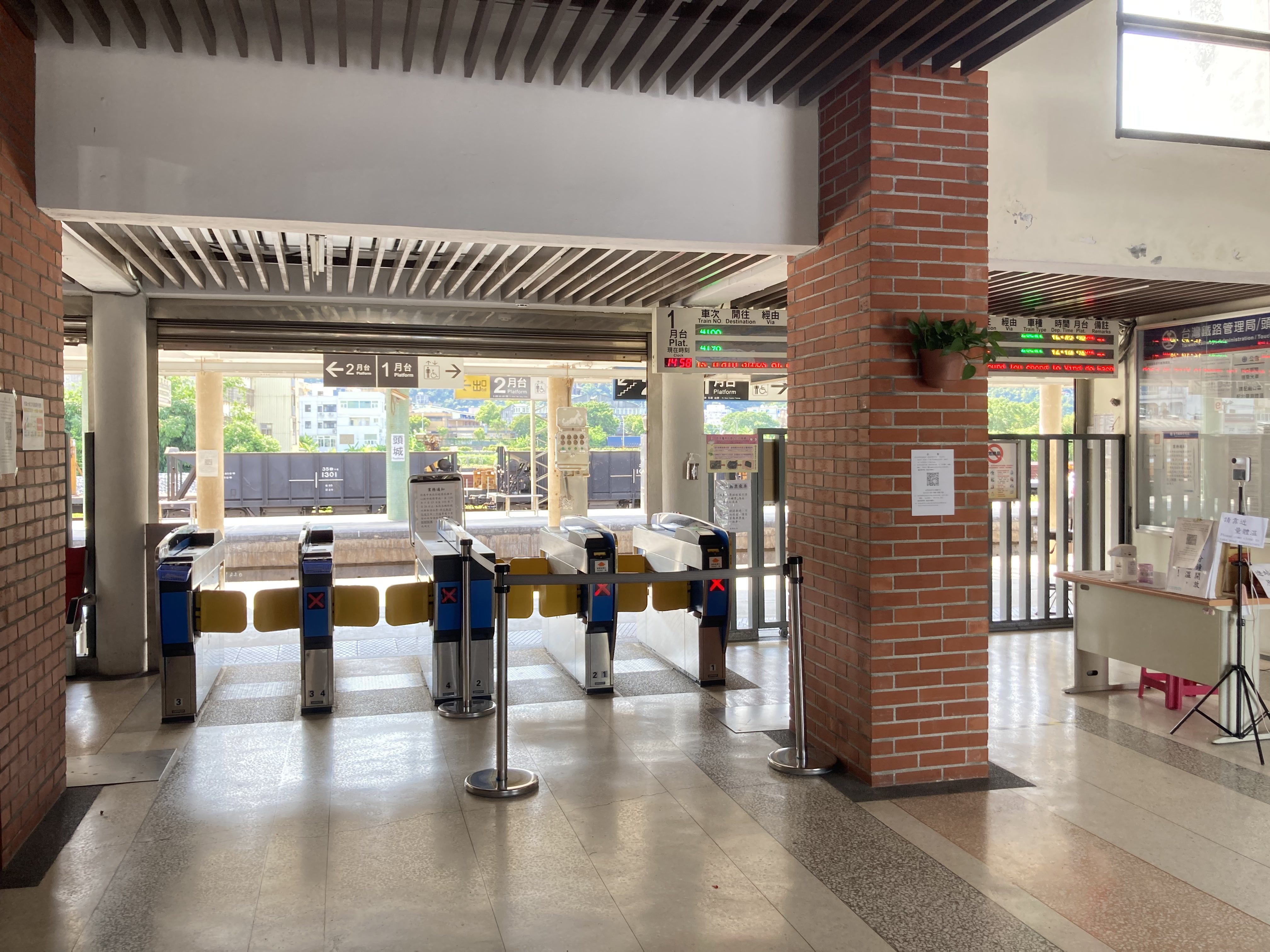 Interior view of a train station entrance in Taiwan with turnstiles and digital displays.