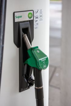 Close-up of a green Super 95 gasoline pump handle at a gas station.