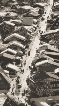 A captivating aerial view of a snowy street lined with traditional Japanese houses, capturing winter's serene beauty.