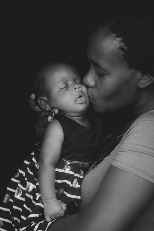 彼女の赤ちゃんにキスする母親のグレースケール写真