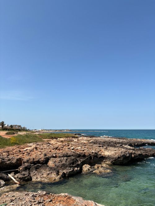 Free A serene view of a rocky coastline and clear blue sky, perfect for travel and nature themes. Stock Photo