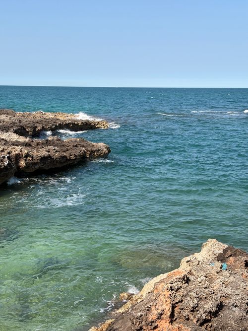 Free A tranquil view of a rocky coastline with clear blue waters under a bright sky. Stock Photo