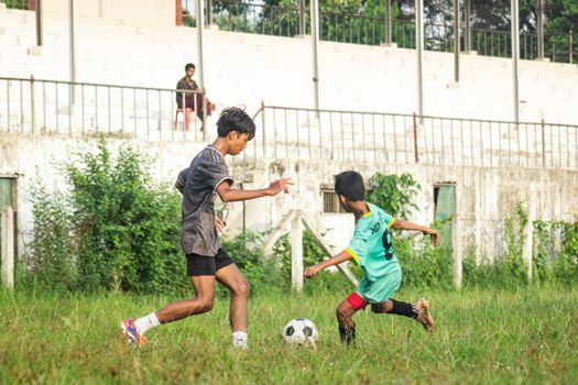 Boys playing soccer on a field in Myawaddy, Myanmar, showcasing action and local culture.