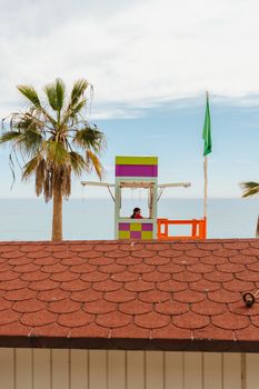 Vibrant lifeguard tower and palm trees on Marbella beach, Spain with ocean view.