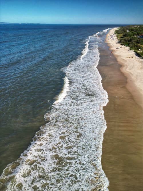 Free Aerial view of a serene beach in Queensland, Australia with waves and clear blue sky. Stock Photo