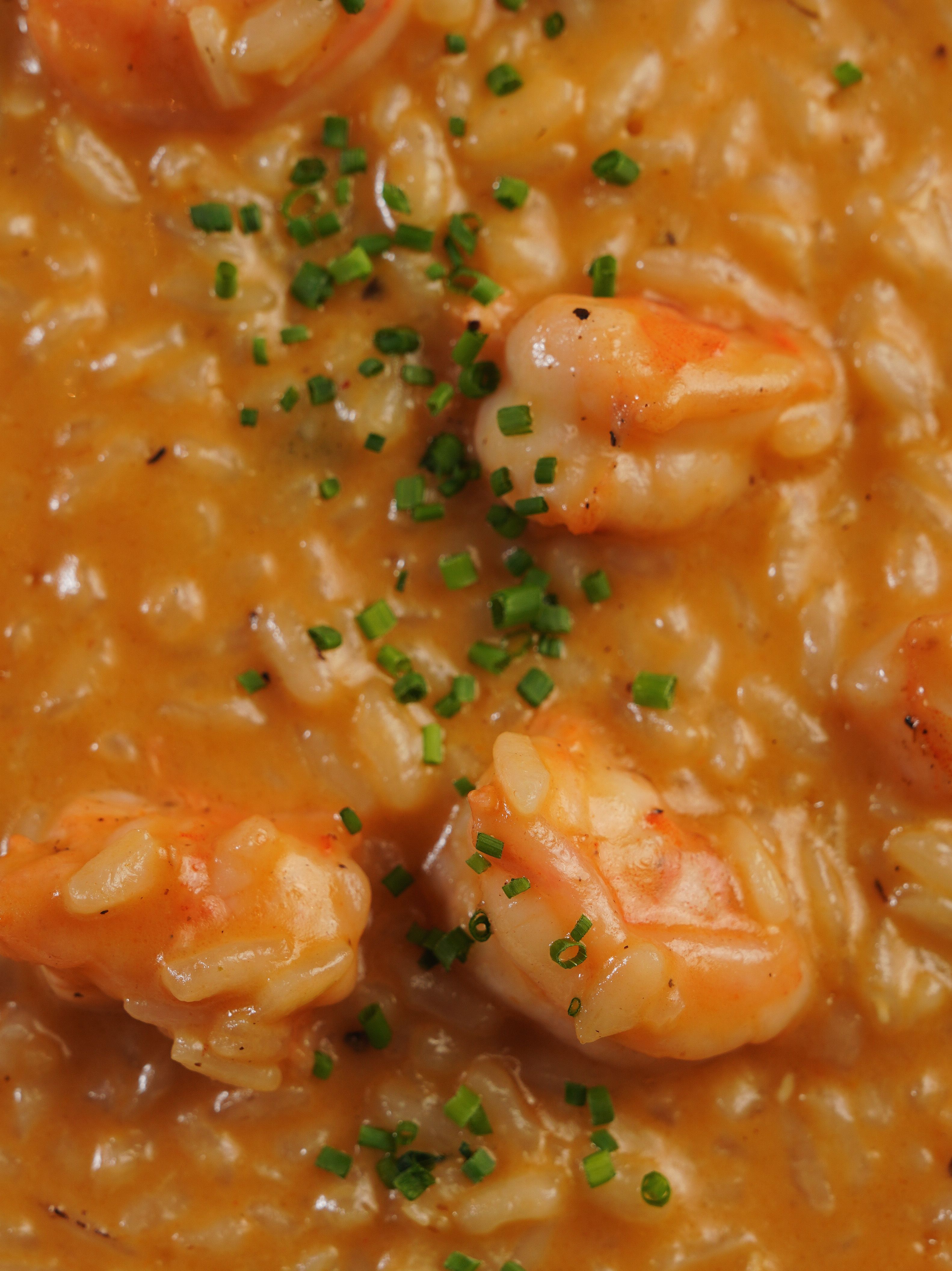 A mouthwatering close-up of creamy shrimp risotto garnished with fresh chives.
