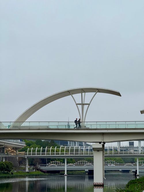 Free A modern bridge over a river with pedestrians on an overcast day in Shanghai, China. Stock Photo