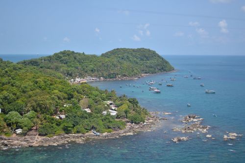 Free Breathtaking aerial view of a lush tropical island surrounded by clear blue waters and scattered boats. Stock Photo