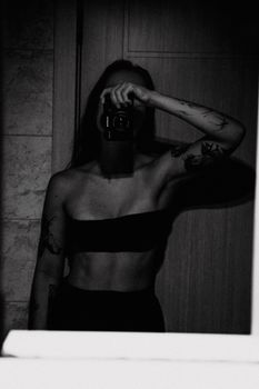 Dramatic black and white self-portrait showcasing tattoos in a mirror reflection.