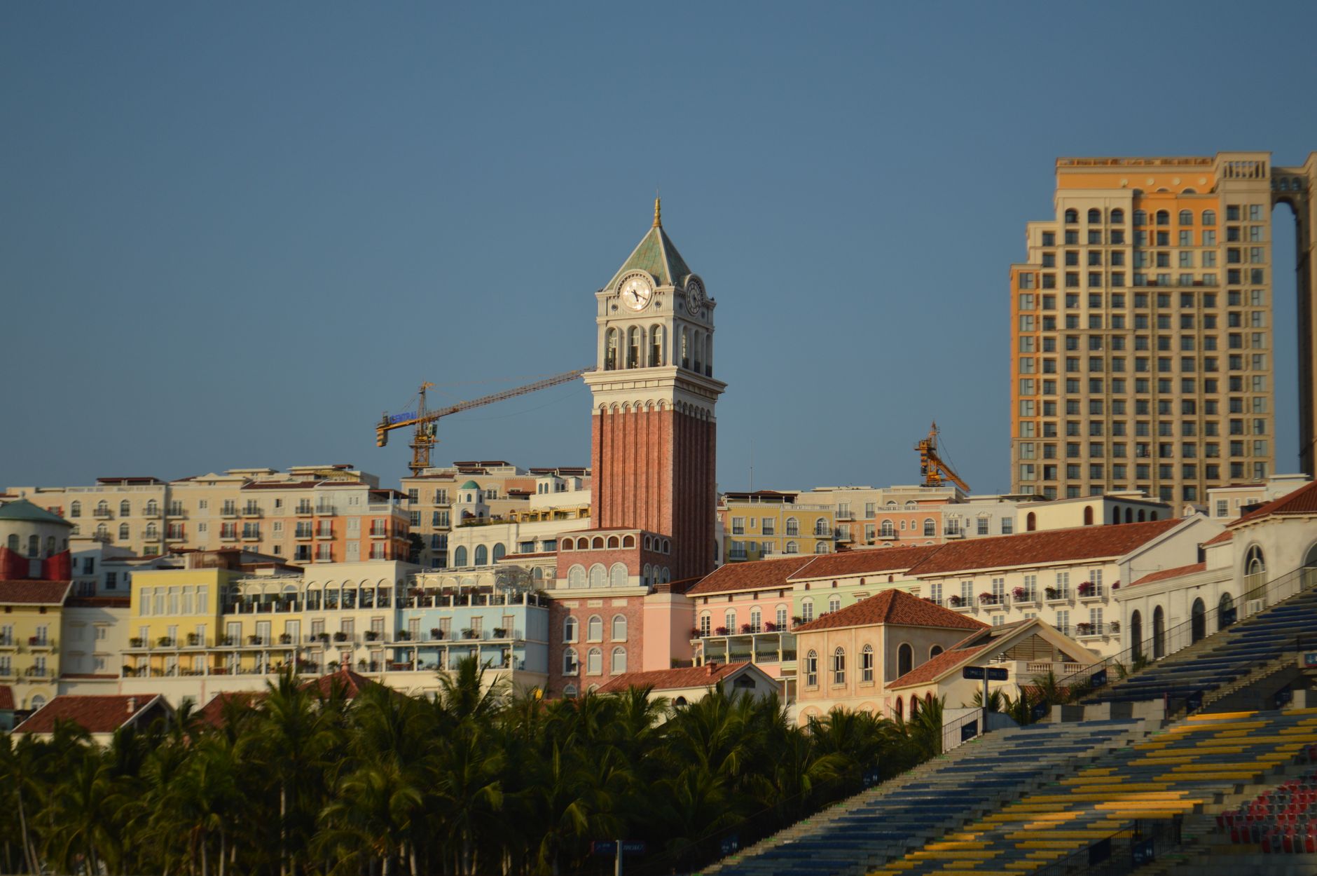 A clock tower surrounded by colorful coastal buildings under a clear blue sky.
