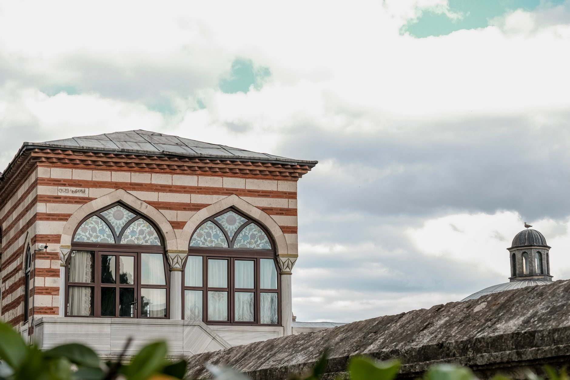 Ottoman style building with arched windows set against a cloudy sky.