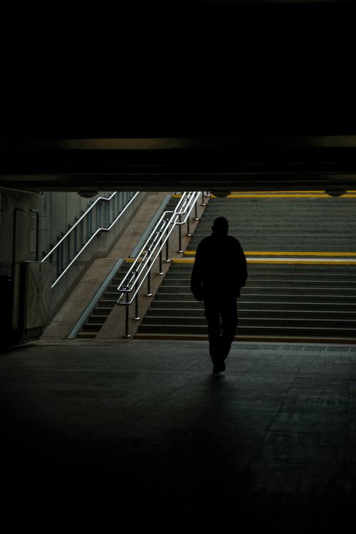 Free A lone figure walks through a dimly lit underground passage, evoking a mysterious urban atmosphere. Stock Photo