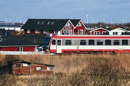 免費 紅色和白色的火車經過一個小鎮 圖庫相片