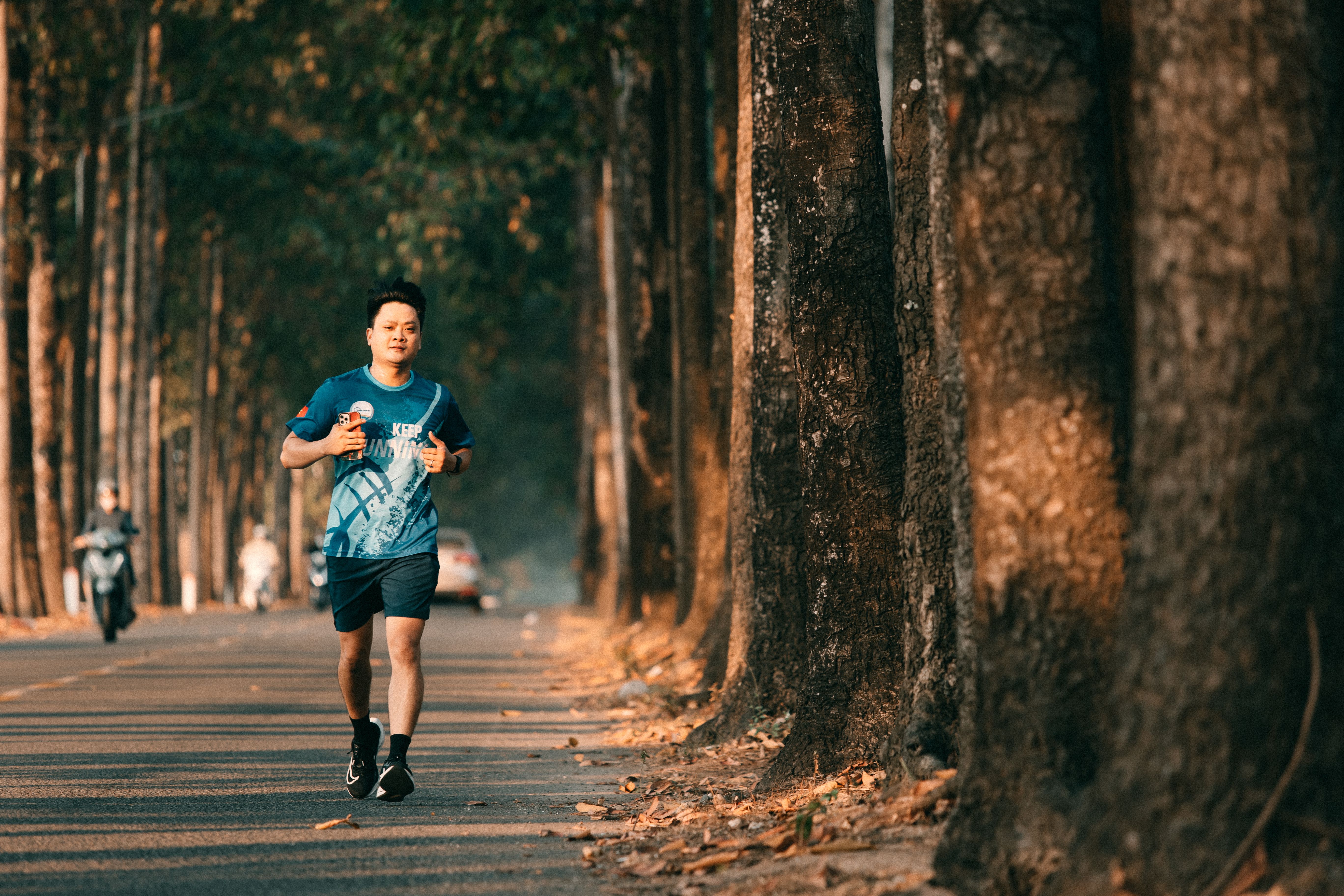 Young Man Jogging on Tree-Lined Path at Sunset