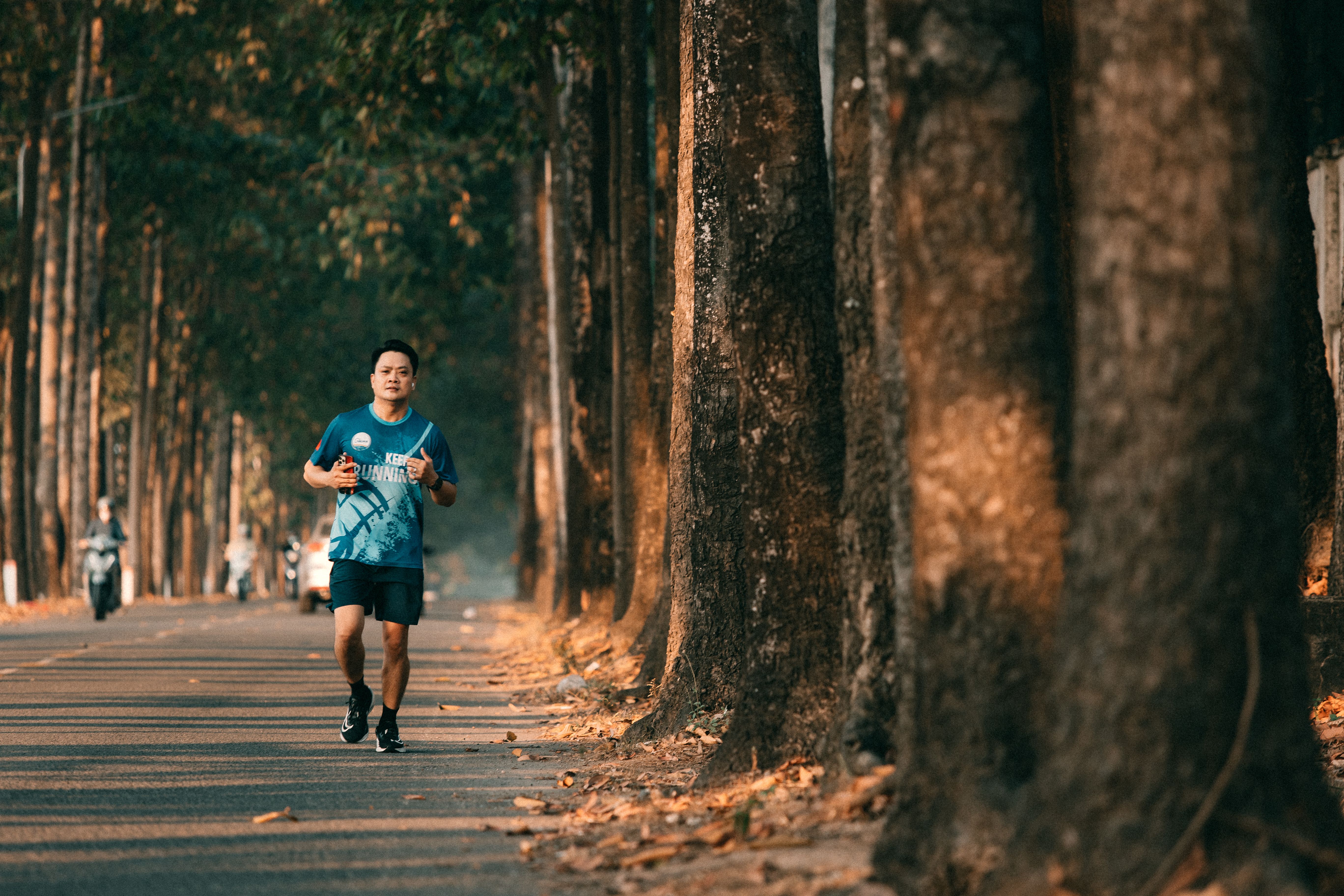 A man jogging along a scenic, tree-lined road, capturing the essence of fitness and nature.