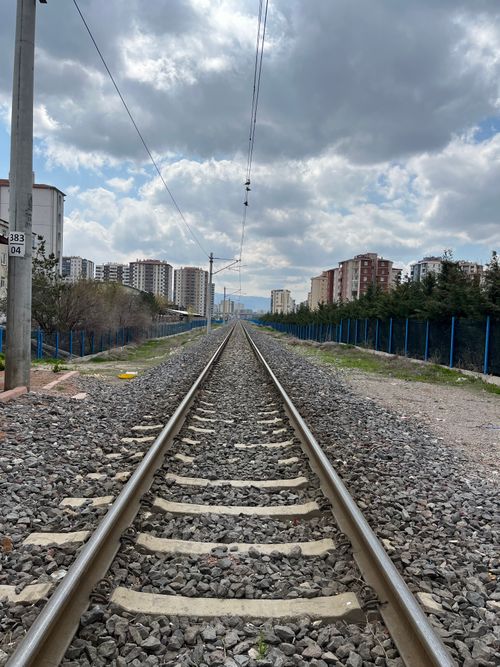 Free A straight railroad track flanked by residential buildings under a cloudy sky. Stock Photo