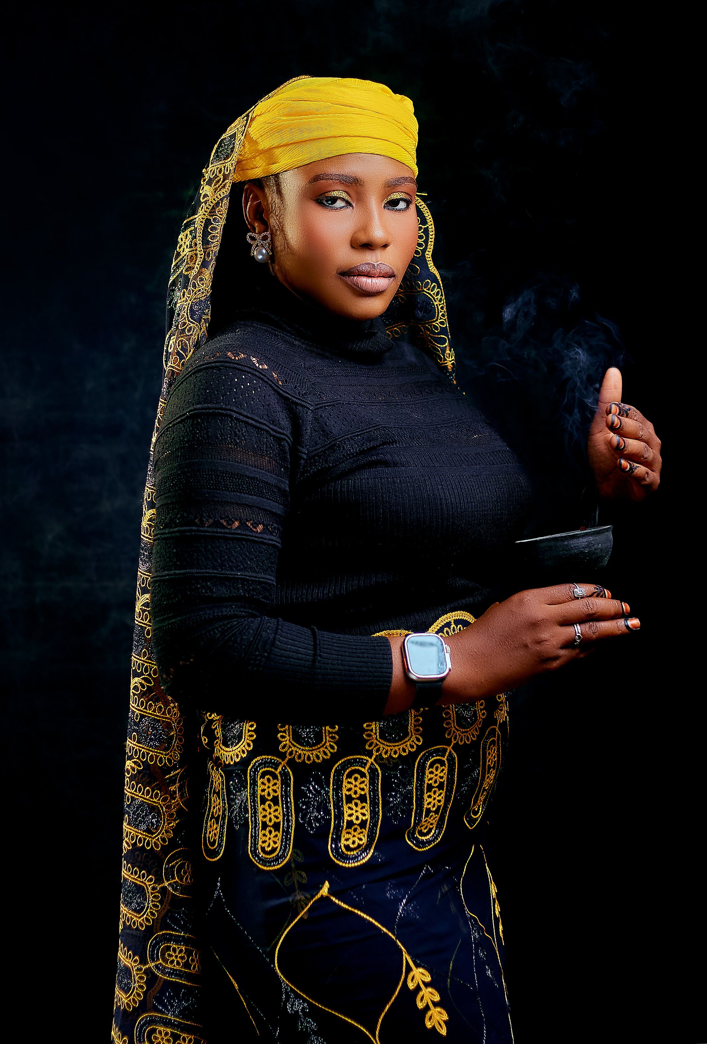 Elegant portrait of woman in vibrant traditional African attire holding a bowl.