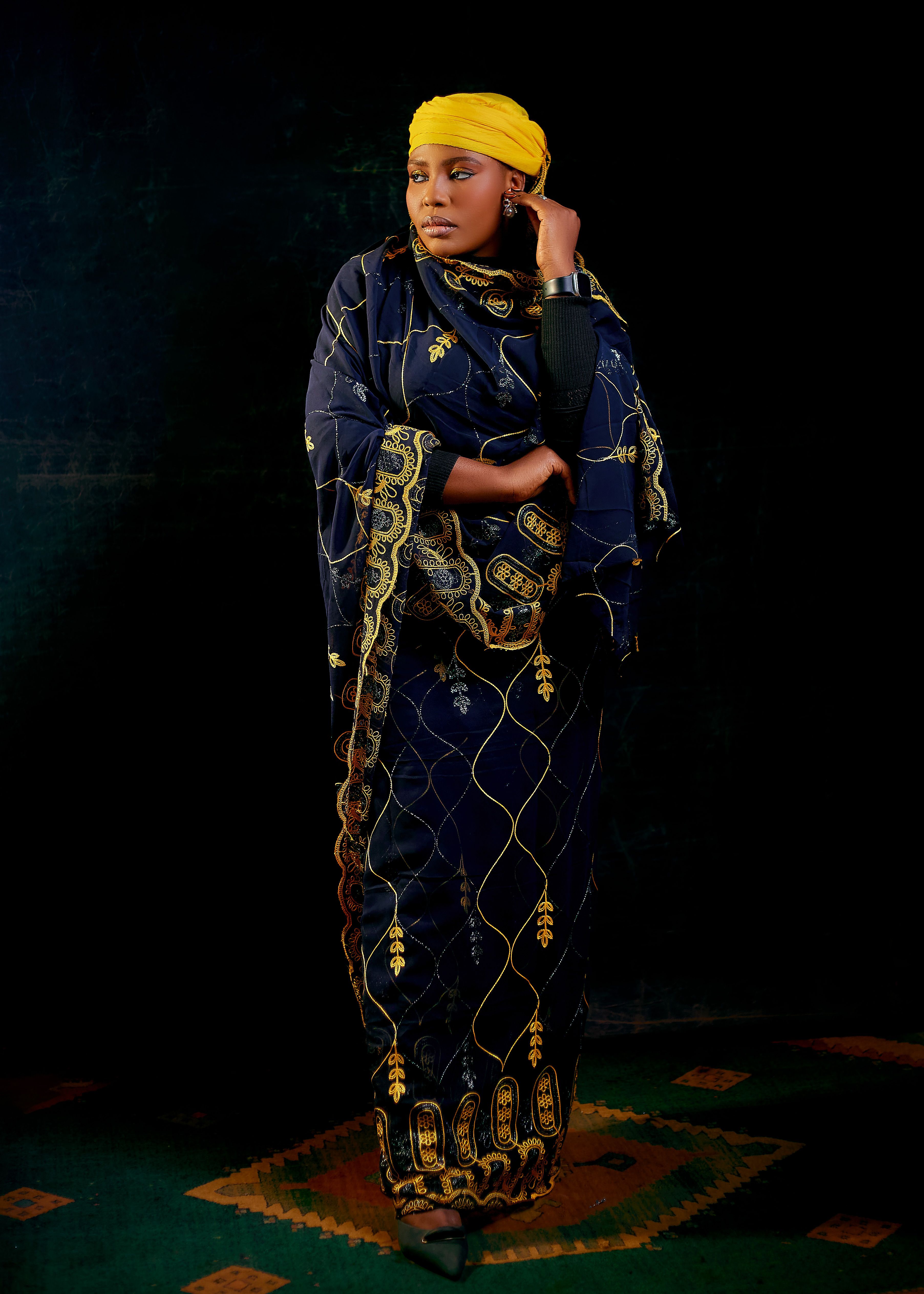 Woman in vibrant traditional African dress against dark background.