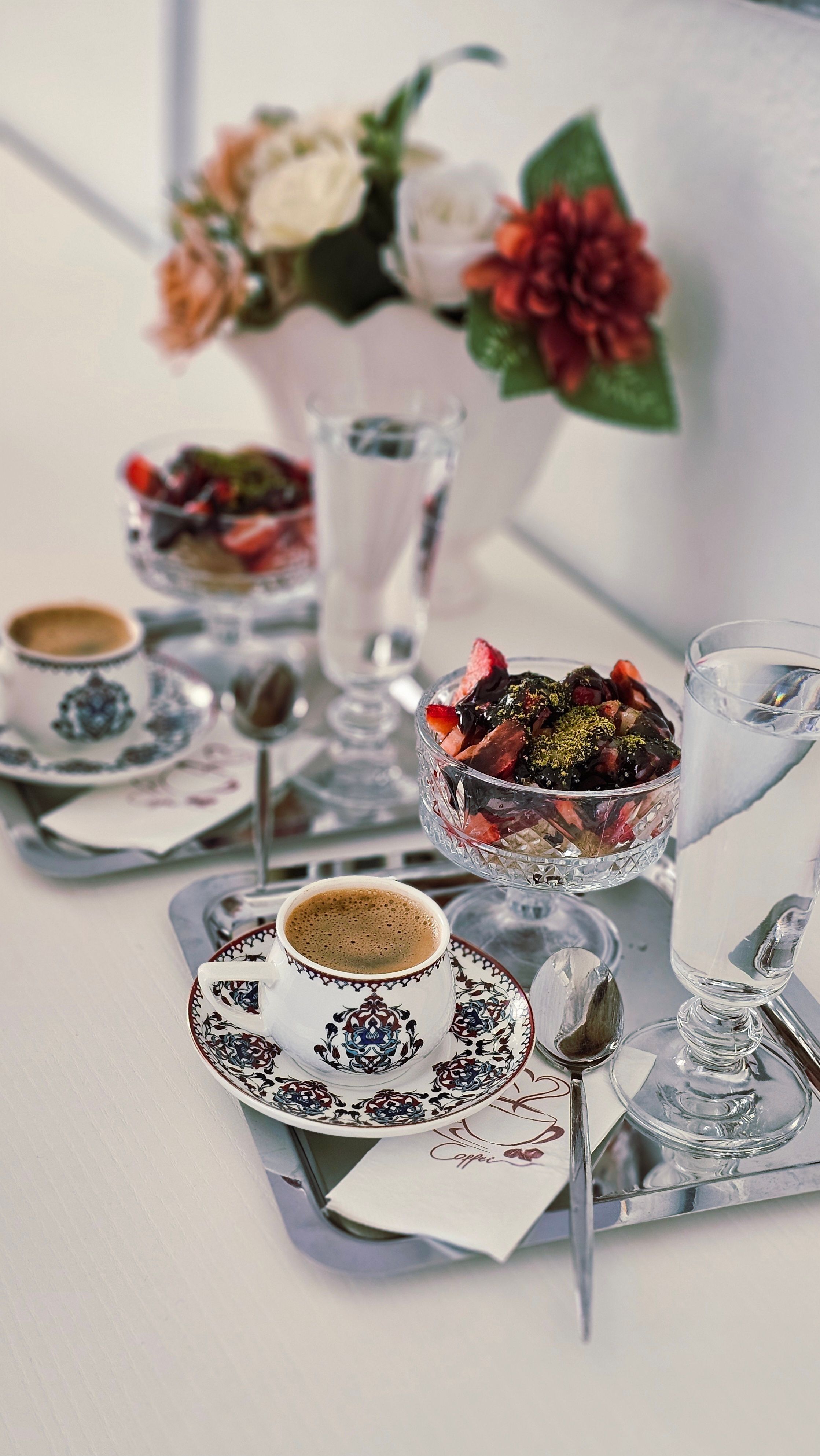 Elegant table setting with coffee cups, desserts, and floral decoration.