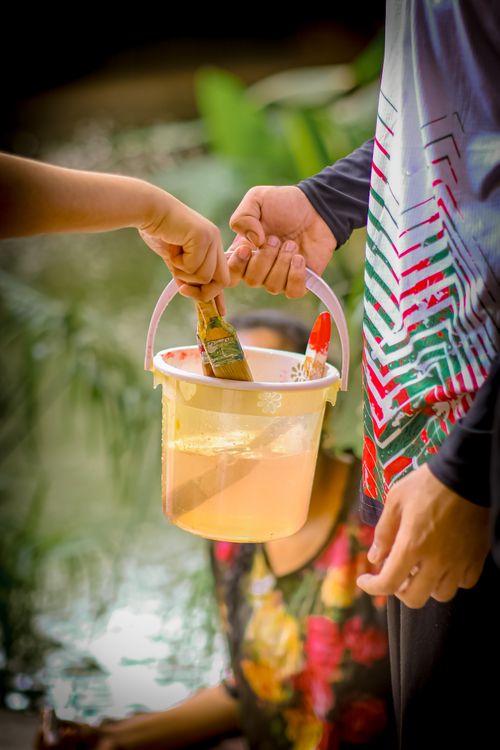 Free Two children holding a bucket and paintbrushes, engaging in an outdoor painting activity. Stock Photo