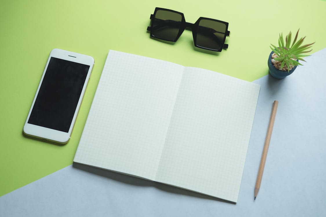 Flat Lay Photography of Smartphone, Printer Paper, Sunglasses, and Pencil