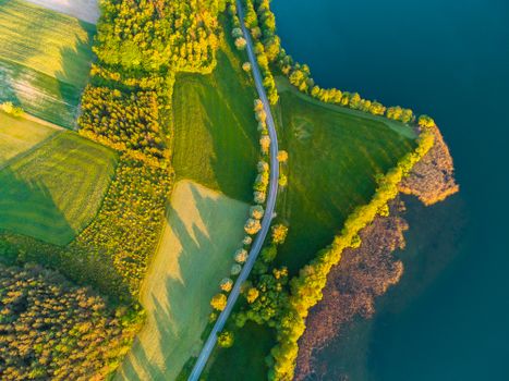 A stunning aerial view of a lush green countryside with winding roads and shimmering blue water.