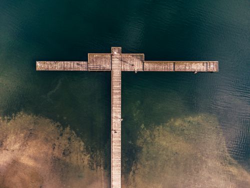 Free Explore the scenic aerial view of a wooden pier extending over a clear, serene lake. Stock Photo