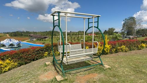 Free Outdoor park scene with a swing, pavilion, and vibrant gardens under a blue sky. Stock Photo