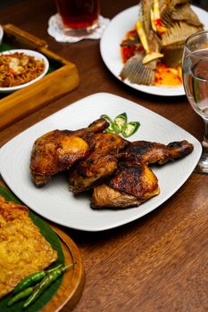 A tantalizing spread of grilled chicken and traditional Indonesian dishes on a wooden table.