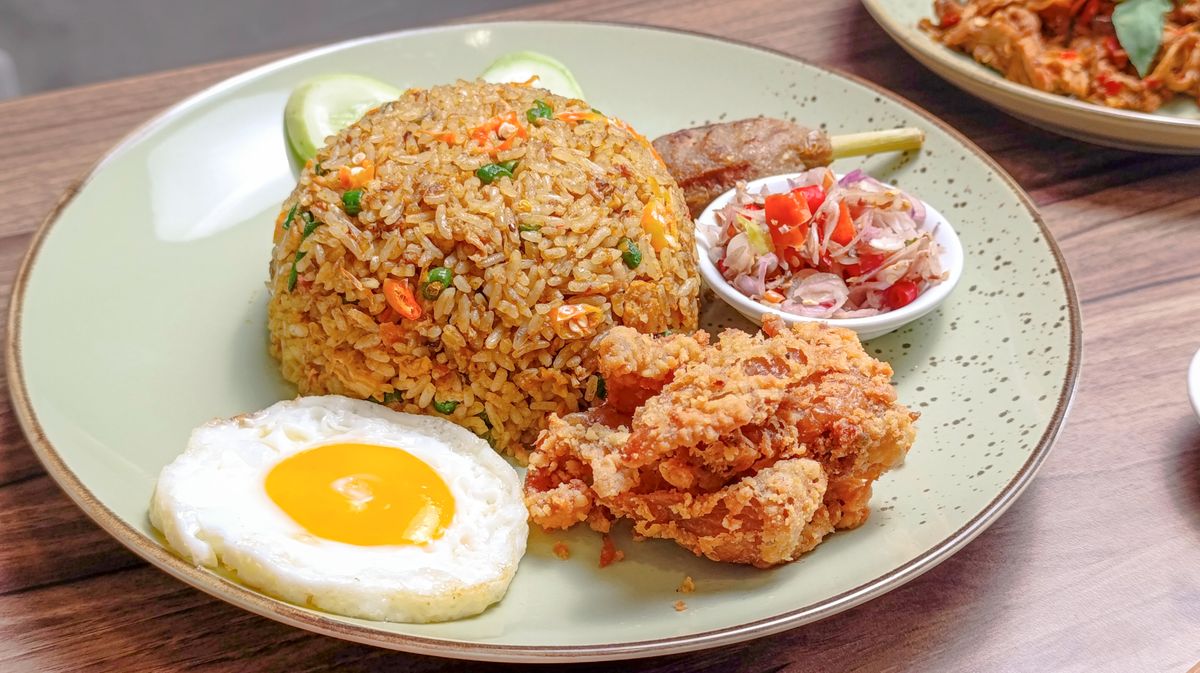 Nasi goreng dome with fried egg, crispy fried chicken, satay skewer and tomato shallot sambal