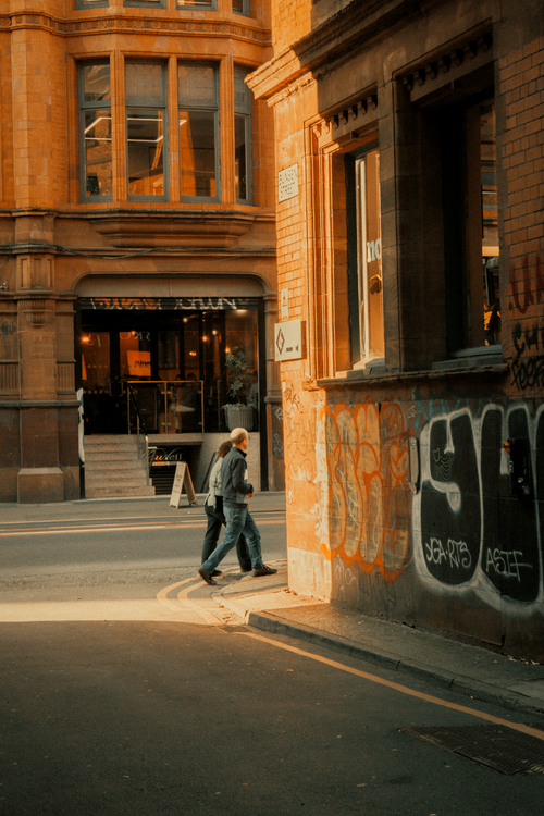 Free A vibrant street scene in Manchester, featuring iconic graffiti and classic architecture in warm sunlight. Stock Photo