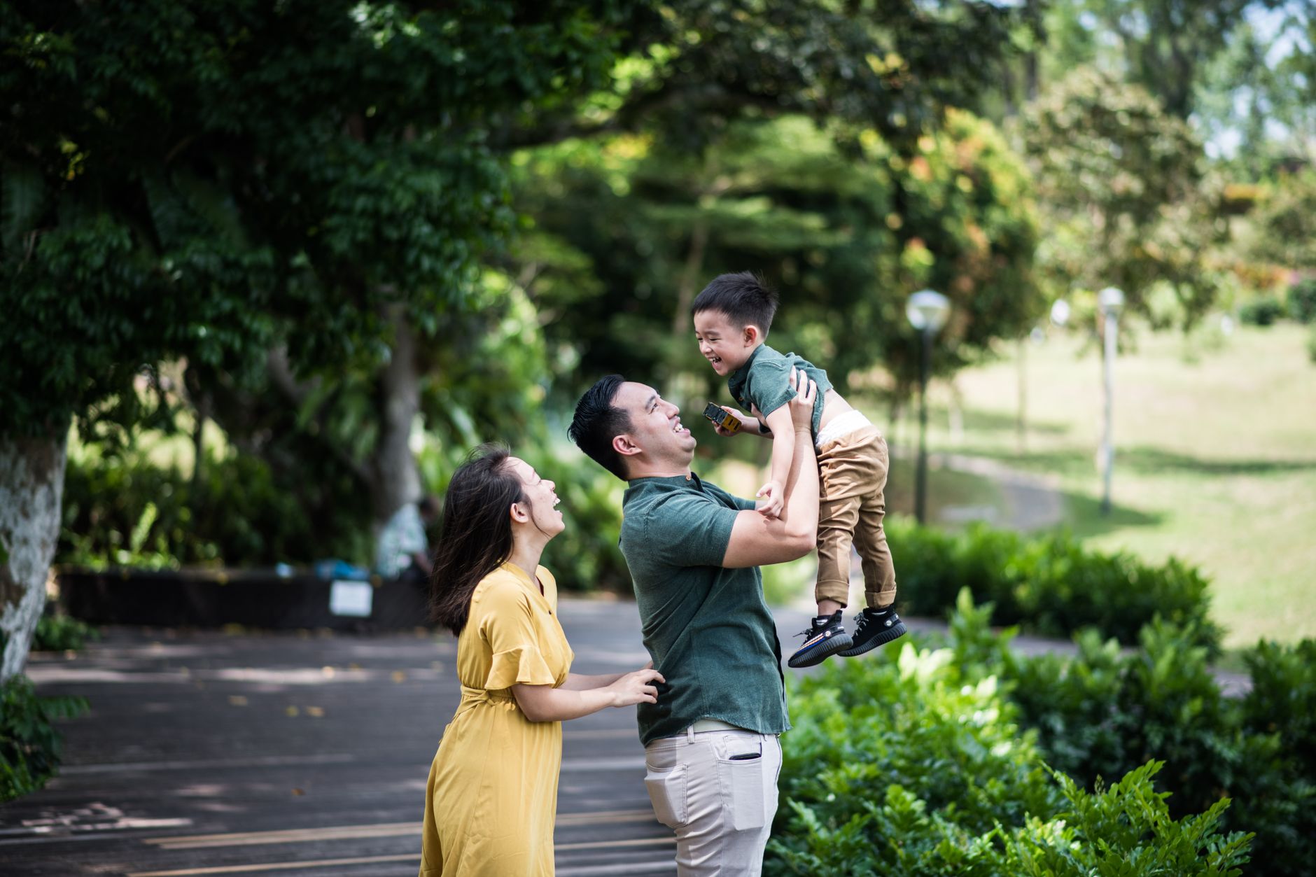 Joyful family bonding moment in a lush Singapore park setting, capturing laughter and love.