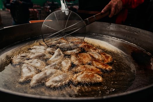 Crispy Argentine empanadas frying in oil outdoors. Street food in Buenos Aires.