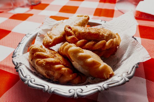 Close-up of fried Argentine empanadas on a red checkered tablecloth, perfect for food themes.