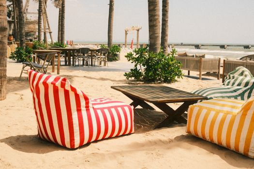 Cozy beach lounge in Phan Thiet, Vietnam with striped bean bags and palm trees.