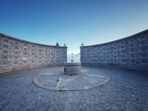 Free A circular stone monument with crosses under a clear blue sky in a mountain setting. Stock Photo