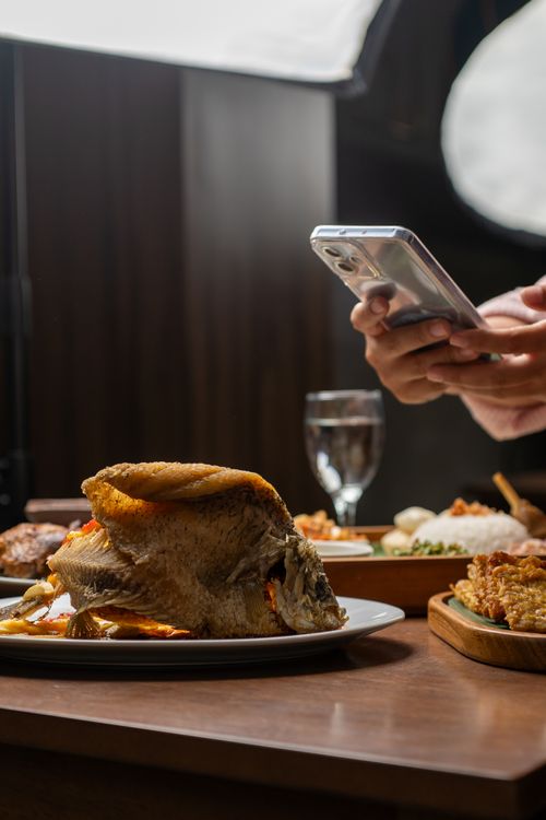 Free A smartphone captures delicious Indonesian fried fish served in a Jakarta restaurant. Stock Photo