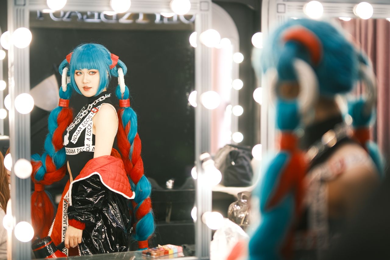 colorful cosplay character poses in a backstage dressing room with bri
