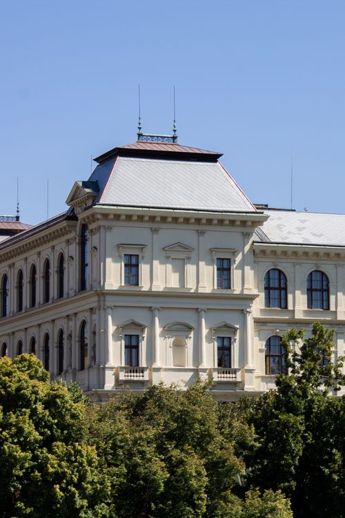 Free Close-up of a historic building with European architectural design surrounded by greenery on a sunny day. Stock Photo