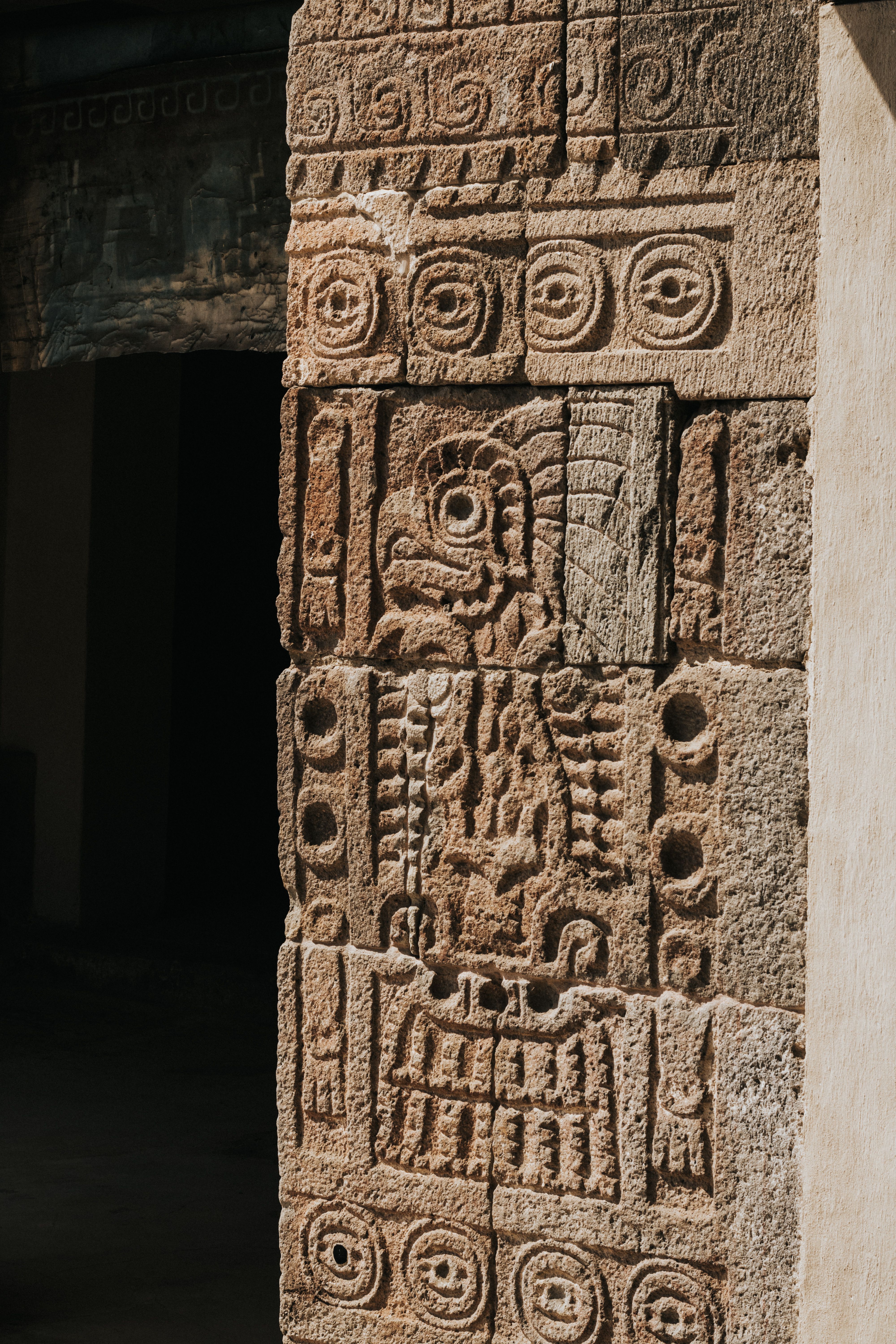 Close-up of intricate Mayan stone carving illuminated by sunlight, showcasing ancient artistry.