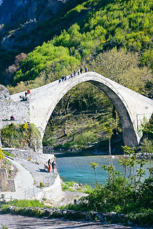 Free A scenic view of an ancient stone bridge spanning the turquoise Aoos River in Konitsa, Greece. Stock Photo