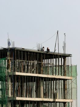 Workers on a high-rise building under construction, showcasing urban development in Ho Chi Minh City, Vietnam.