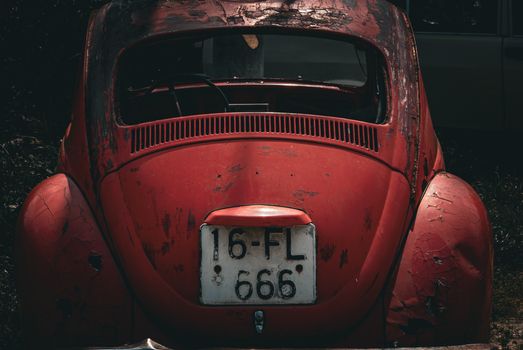 Aged red Volkswagen Beetle showing rustic charm with peeling paint.