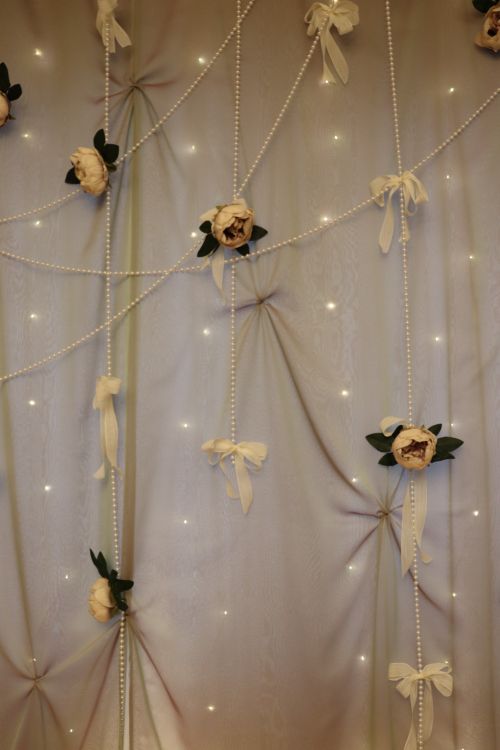 Free Sophisticated floral decorations on a curtain with beaded garlands and warm lighting. Stock Photo